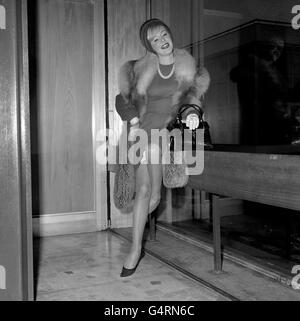 Sängerin Kathy Kirby, in einem rostfarbenen Kleid und Mantel mit rotem Fuchspelzkragen, am Flughafen London, bevor sie zu einem Weihnachtsurlaub nach Barbados aufmacht. Stockfoto