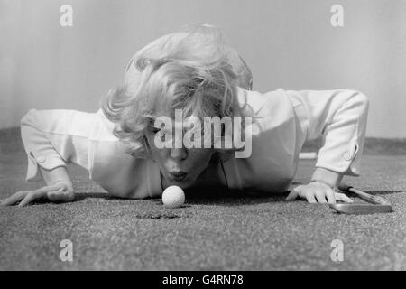 Sängerin Kathy Kirby bläst ihren Golfball näher an das Loch auf dem Old Links Golf Course, Lytham St. Anne's. Die Sängerin hat den Kurs in den Pausen ihrer Sommersaison in Blackpool besucht. Nach Angaben des lokalen Profis hat sie gute Fortschritte gemacht, seit sie den Sport begann. Kathy sagte: „Ich war schon immer an dem Spiel interessiert, aber ich kam nie dazu, es auszuprobieren. Viele andere Showbusiness-Leute scheinen Golf zu spielen, also dachte ich, dass ich genauso gut mitmachen könnte. Stockfoto