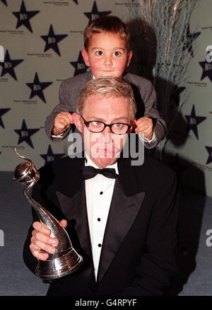 BBC-Kinderschauspieler Scott Chisholm zieht Paul O'Grady, alias Lily Savage, bei den National Television Awards in der Royal Albert Hall in London die Ohren. Stockfoto