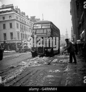 Ein Mann mit Schaufel reinigt den Strand of Slush in London nach einem heftigen Schneesturm, der Schnee über das Land gefegt hat. Stockfoto