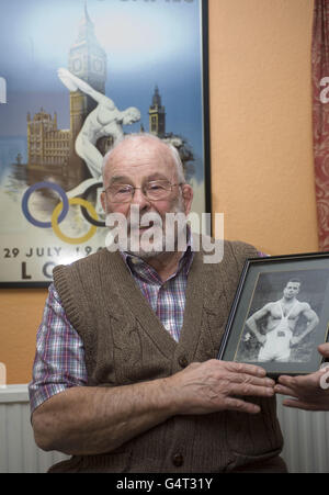 Der ehemalige olympische Ringer Ray Myland aus Leigh-on-Sea, Essex, der bei den Olympischen Spielen 1948 in London mit einem Bild von sich selbst bei den Olympischen Spielen 1952 in Helsinki teilnahm. Stockfoto