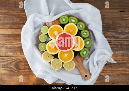 Scheiben von Zitrusfrüchten angeordneten runden Schneidebrett mit eleganten Seidentuch. Ansicht von oben. Stockfoto