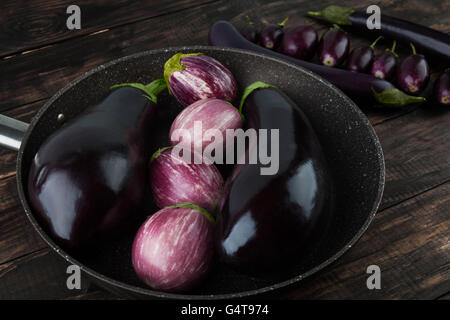 Auberginen Sorten auf Holztisch - klassische schwarze Magie, violett gestreift, Baby, und japanische Auberginen Stockfoto