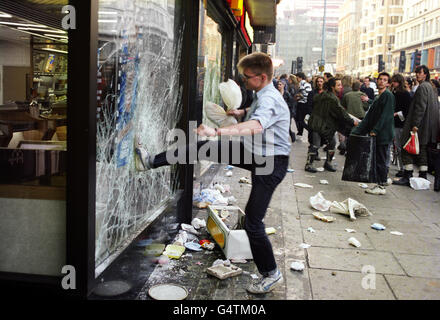 Ein Protestler tritt während der Unruhen in London, nachdem Anti-Umfrage-Steuerdemonstrationen ausgebrochen waren, in das Fenster eines Fast-Food-Stores in der Lower Regent Street. Stockfoto