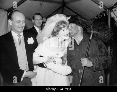 Lord Montagu sieht mit einem Lächeln zu, wie seine Braut, die ehemalige Miss Belinda Crossley, einen Glückskuss vom Schornsteinfeger Frank Miles bekommt, als sie die Abbey Church aus dem 13. Jahrhundert in Beaulieu, Hampshire, nach ihrer Hochzeit verlässt. Stockfoto