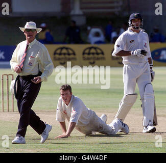 Der Schiedsrichter Rudi Koetzen geht aus dem Weg, während der englische Spin-Bowler Graeme Swann den Ball von Greg Smith am dritten Tag eines dreitägigen Spiels gegen eine südafrikanische Einladung XI im St. George's Park, Port Elizabeth, an die Grenze zieht. Stockfoto