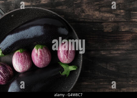 Auberginen in Pfanne auf rustikalen Holztisch nass. Draufsicht mit Textfreiraum Stockfoto