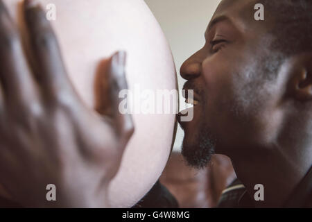 Papa küsst Babybumps und lächelt. Stockfoto