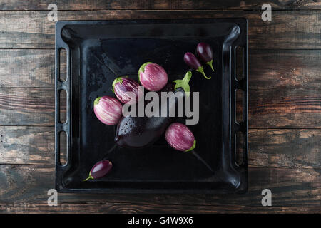 Auberginen - schwarze Magie, Baby und lila gestreifte Auberginen in rustikalen Backblech nass. Draufsicht mit Textfreiraum Stockfoto