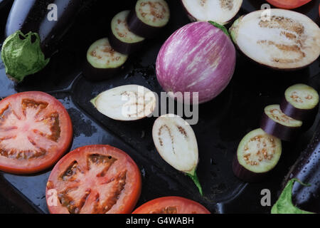Ganze und geschnittene Auberginen und Tomaten auf rustikalen Backblech Tablett Closeup. Geringe Schärfentiefe Stockfoto