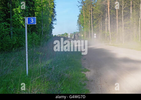 Linkes Foto Straßenschild - 3 km. Auf der anderen Straßenseite eine Staubwolke aus dem Fahrzeug reisen. Stockfoto