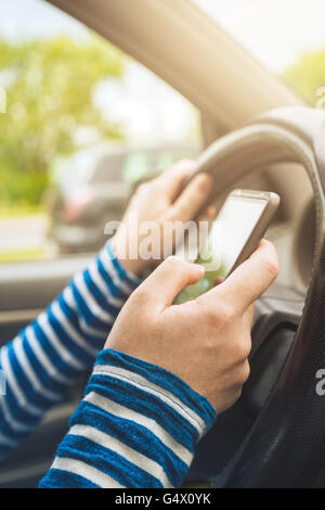 Autofahrerin Auto und SMS Nachricht auf Smartphone, mit Handy-Gerät während der Fahrt, gefährlich und riskant Verhalten in tr Stockfoto