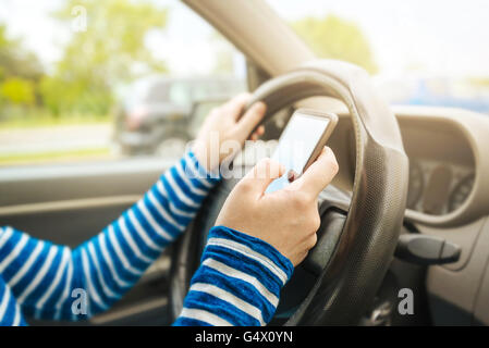 Autofahrerin Auto und SMS Nachricht auf Smartphone, mit Handy-Gerät während der Fahrt, gefährlich und riskant Verhalten in tr Stockfoto