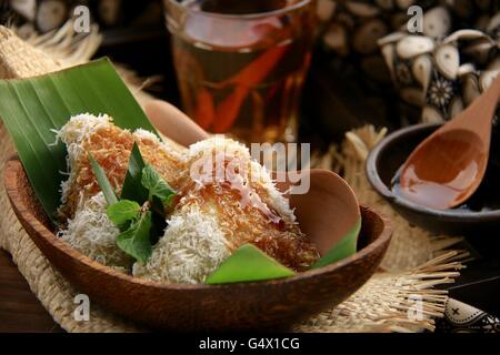 Lupis, traditionelle javanischen glutinous Reis Kuchen mit geriebener Kokosnuss und Palmzucker Sirup. Im zeitgenössischen javanischen Set vergoldet. Stockfoto