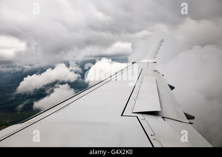 VEREINIGTES KÖNIGREICH. Sehen Sie aus einem Flugzeug-Fenster, wie es an Land durch niedrige Wolke steigt Stockfoto