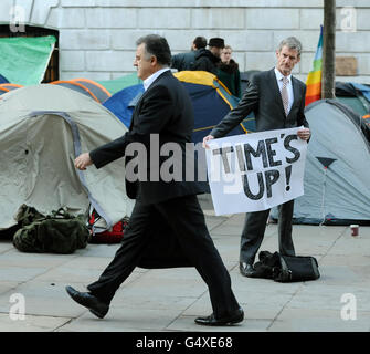 Büroangestellte passieren antikapitalistische Demonstranten, die vor der St Paul's Cathedral im Zentrum von London im Rahmen der "Occupy the London Stock Exchange"-Demonstration lagerten. Stockfoto