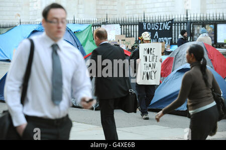 Büroangestellte passieren antikapitalistische Demonstranten, die vor der St Paul's Cathedral im Zentrum von London im Rahmen der "Occupy the London Stock Exchange"-Demonstration lagerten. Stockfoto