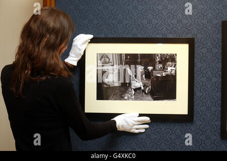 Die Mitarbeiterin der Royal Collection, Rachel Woolen, hängt mit einem ihrer Corgis, Teil der Queen, an ihrem Schreibtisch im Buckingham Palace ein Foto aus der Zeit von 1959 von The Queen: 60 Fotografien für 60 Jahre Ausstellung im Windsor Castle. Stockfoto