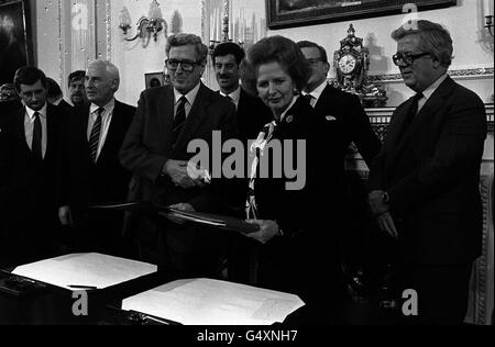 Premierministerin Margaret Thatcher und der irische Premierminister Dr. Garret FitzGerald, unter der Beobachtung von Geoffrey Howe, schütteln sich nach der Unterzeichnung des angloirischen Ulster-Abkommens im Hillsborough Castle, Belfast, die Hände. Stockfoto