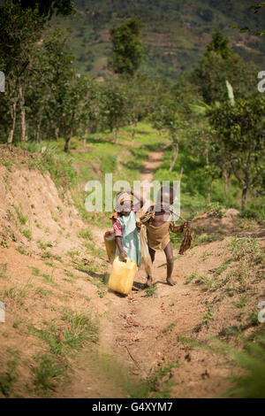 Kinder tragen Gießkannen ein Dorf Weg in Kasese District, Uganda, Ostafrika. Stockfoto