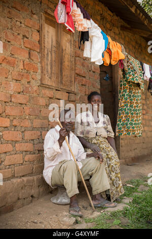 Mann und Frau sitzen vor ihrem Haus in Kasese District, Uganda, Ostafrika. Stockfoto