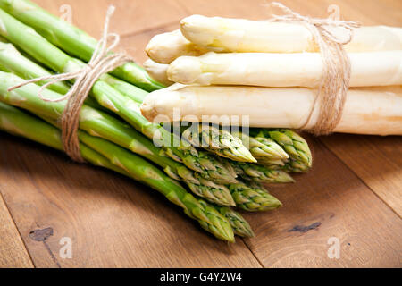 rohen Spargel Trauben, grün und weiß, auf Holzboden Stockfoto