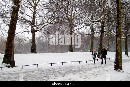 Ein paar Spaziergang durch den St James's Park in London, als ein Großteil Großbritanniens zu einer Schneedecke aufwachte, nachdem der große Frost Deponien von bis zu 16 cm brachte, Flugzeuge geerdet und Straßen- und Bahnstörungen verursachte. Stockfoto