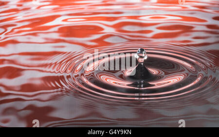Wassertropfen gefangen übereinander auf bunten orange Hintergrund Stockfoto