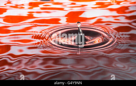Wassertropfen in hellen orange farbigen Wellen erfasst Stockfoto