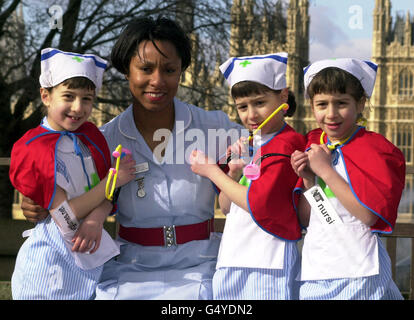 Die Krankenschwester Pat Stanford aus dem Kinderkrankenhaus mit 7-jährigen Drillingen (L-R) Gabrielle, Alexandra und Eleanor Grant aus St. Albans, außerhalb des St. Thomas' Hospital, London, wo die Regierung eine große Rekrutierungswelle im NHS angekündigt hat. * die drei jungen Mädchen aus St. Albans, die in Krankenschwestern-Uniformen gekleidet sind, um zu zeigen, dass der Pflegeberuf nicht tot ist. Die Aktion wird von einer hochkarätigen Werbekampagne begleitet. Stockfoto