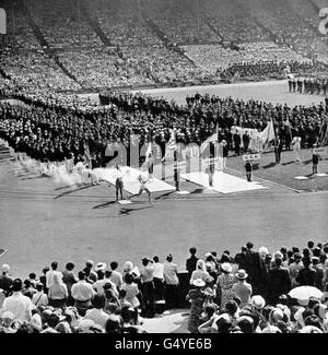 Der britische 400-Meter-Läufer John Mark (Medizinstudent an der Cambridge University) trägt die Olympic Fackel an den Fahnenträger und den Olympischen Teams vorbei, während er sich auf der Strecke durch die Strecke macht, bevor er die olympische Flamme entzündet. Der Flaggenträger Großbritanniens ist der Fechter John Emrys Lloyd. Stockfoto