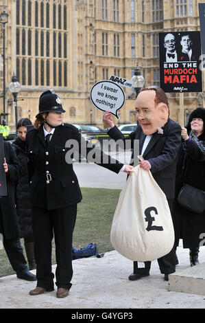 Demonstranten mit James-Murdoch-Kopf und Polizeiuniform demonstrieren im Rahmen einer Kampagne der Organisation Avaaz gegen das Murdoch-Medienreich vor dem Oberhaus. Stockfoto