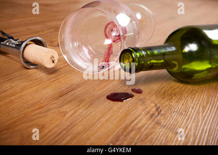 Rotwein Flecken auf Holzböden mit schmutzigen Glas Wein, Korkenzieher und leere Weinflasche, Stockfoto