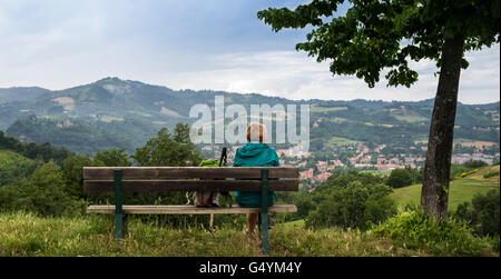 Frau Walker sitzen auf einer Bank mit Blick auf Sasso Marconi in der Nähe von Bologna, Italien. Stockfoto