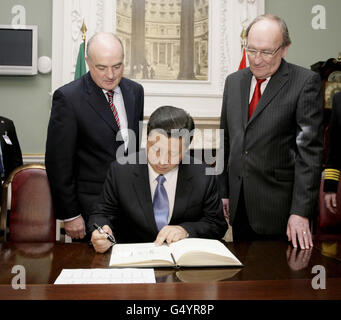 S.E. Xi Jinping , Vizepräsident der Volksrepublik China, als er das Besucherbuch mit Hintergrundinformationen über Senator Paddy Burke (links) Cathaoirleach und Sean Barrett (rechts) T.D. unterschreibt Ceann Comhairle, als der Vizepräsident am dritten und letzten Tag eines dreitägigen Besuchs in Irland Leinster House besuchte. Stockfoto