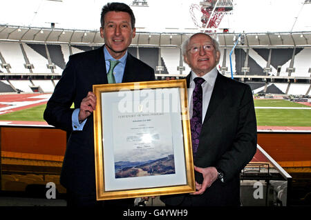 Lord Sebastian Coe, Vorsitzender von LOCOG (links), wird vom irischen Präsidenten Michael D Higgins während eines Besuchs im Olympiastadion in Stratford, London, eine Urkunde überreicht. Stockfoto