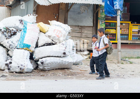 Nepal, Western Region, Besisahar, Annapurna Circuit - Kathmandu nach Bhulbhule - Schüler auf dem Weg nach Hause in Besisahar neben Säcke Leergut Flaschen Stockfoto