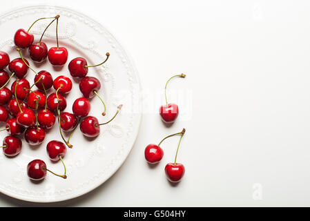 Frische Kirschen auf einen Teller und weißen Hintergrund. Stockfoto