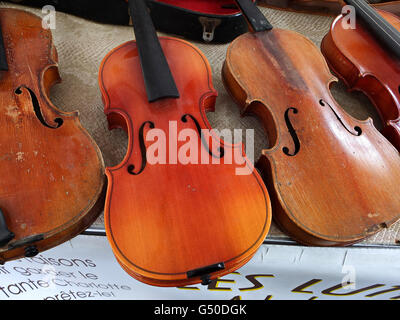 Eine Reihe von gut verwitterte Geigen auf einem französischen Flohmarkt außerhalb von Paris. Stockfoto