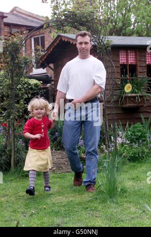 PC Dale Nufer von der Charing Cross Polizeiwache mit seiner dreijährigen Tochter Elke im Garten seines Familienhauses in Winchmore Hill, North London. * PC Nufer wurde mit einer verrenkten Schulter zurückgelassen, als ein Schläger seinen Schild ergriff und seine Schulter während der Demonstration am 1. Mai aus dem Sockel riss. Stockfoto