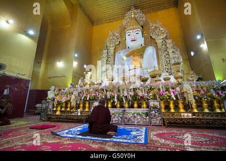 Ein Mönch betend vor einer großen Sitting Buddha Statue, Su Taung Zahlen Pagode, Mandalay, Mandalay Region, Myanmar Stockfoto