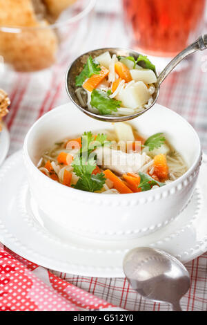 Vorlage-Hühnersuppe mit Nudeln, Kartoffeln und Karotten in einem weißen Kelch auf eine Tischdecke in eine Zelle Stockfoto