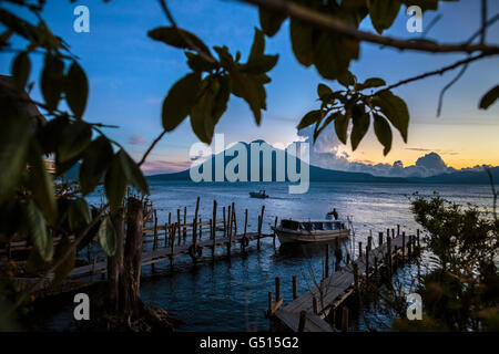 Die Sonne geht über Lago de Atitlan in Guatemala, und die letzten Wassertaxis bringen Touristen zu den Docks in Panajachel in der Abenddämmerung. Stockfoto