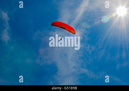 niedrigen Winkel Ansicht der Person motor Paragliding gegen einen klaren, blauen Himmel und strahlende Sonne mit Blendenfleck Stockfoto