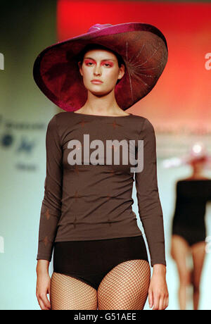 Ein Model mit Outfit und Hut eines Diplom-Designers des London College of Fashion läuft auf dem Laufsteg während der Graduates' Fashion Show auf der Planet 2000 in London. Stockfoto