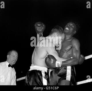 Der britische Herausforderer Dave Charnley (l) pinnt seinen amerikanischen Gegner Joe Brown während des Their Fight gegen die Seile, beobachtet von Schiedsrichter Tommy Little. Joe Brown gewann nach 15 Runden auf Punkte. Der Kampf wurde 1961 Ring Magazine Fight of the Year gewählt. Stockfoto