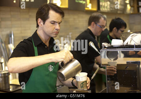 Jimmy Carr legt eine grüne Schürze an, um Amelia Hemphill aus London bei Starbucks in der Conduit Street, London, zu bedienen, um ihren neuen stärkeren britischen Latte zu lancieren. Stockfoto