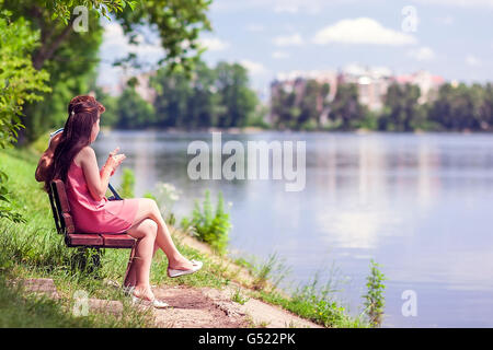 Paar, sitzen auf einer Bank am See an einem sonnigen Sommertag Stockfoto
