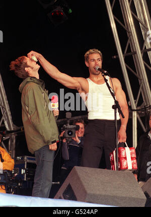 Der ehemalige Eastenders-Schauspieler Joe Absolom wird von Evil Jared, der amerikanischen Hip-Hop-Rockband Bloodhound Gang, zu warmen Dosen von 'DR Pepper' herausgefordert, während die Band auf der Bühne des Glastonbury Music Festival 2000 in Pilton, Somerset, auftrat. Stockfoto