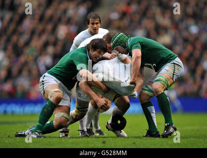 Der englische Ben Morgan (Mitte) verliert seine Kopfbedeckung, nachdem er während des RBS 6 Nations-Spiels im Twickenham Stadium, London, von dem irischen Donncha O'Callaghan (links) und dem irischen Sean O'Brien (rechts) angegangen wurde. Stockfoto